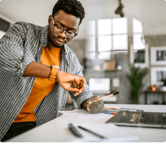 man at desk checking time on wristwatch