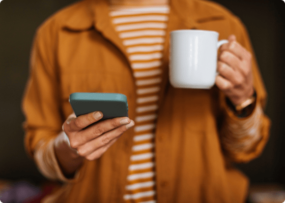 man holding coffee mug and mobile