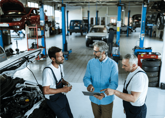Kunde spricht mit Mechanikern in einer Autowerkstatt