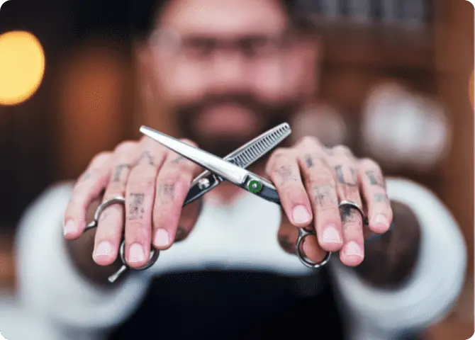 Ein Barbier zeigt seine Haarschneidewerkzeuge und Scheren