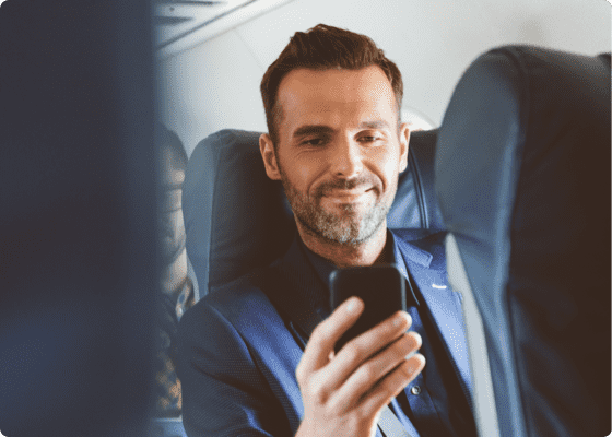 Um homem sentado num avião com um telemóvel