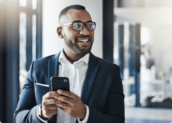 Un uomo in giacca sorridente che tiene un cellulare nelle mani