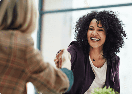 A cheerful woman shaking hands with another