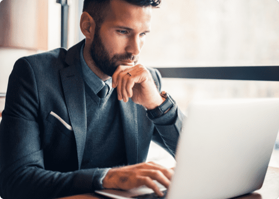 A man looking at the laptop with his hands on chin