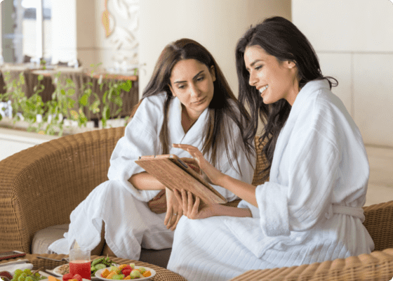 Due donne sedute che discutono guardando un tablet