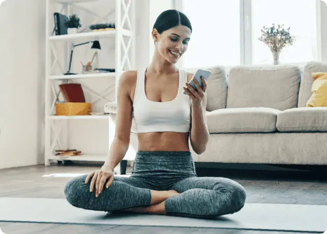 A woman sitting on the floor looking at her phone