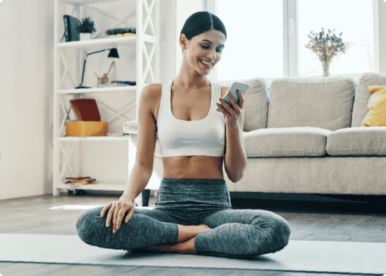 A woman sitting on the floor looking at her phone