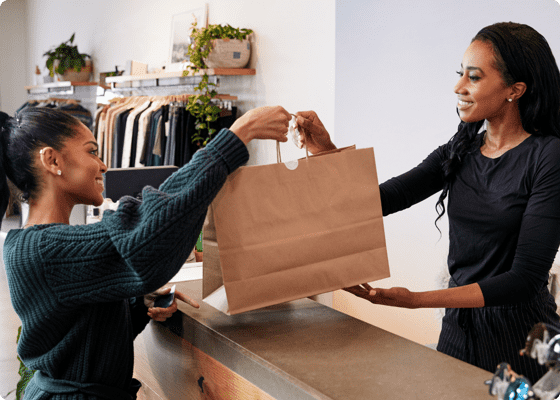 A woman handing over the bag to another in store