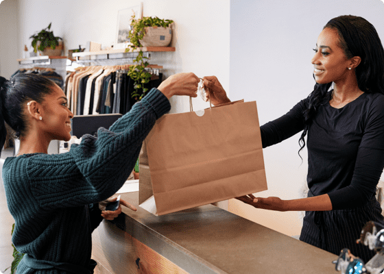 Une femme remettant le sac à une autre dans le magasin.