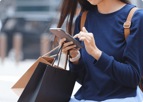 A woman operating her mobile holding shopping bags