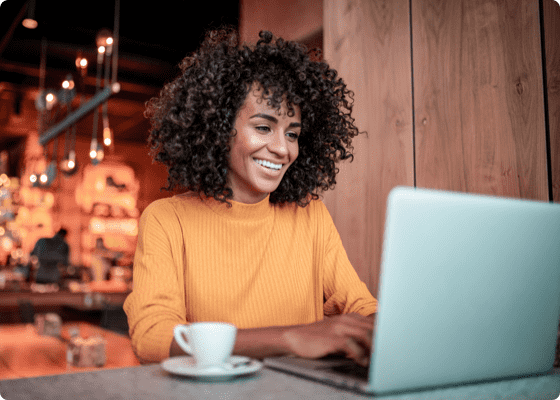 Uma mulher que trabalha num café com o seu portátil